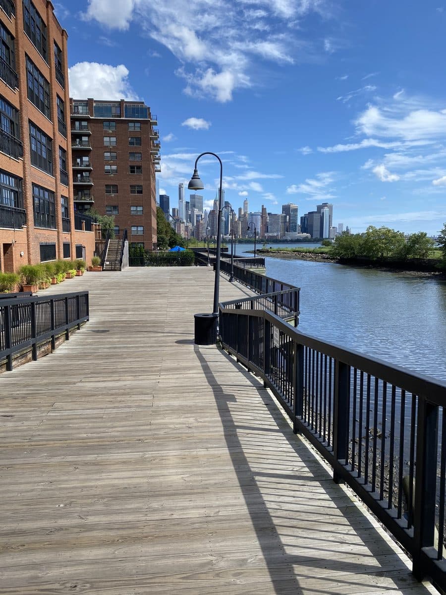 Bright Hudson waterfront boardwalk with the New York skyline beyond